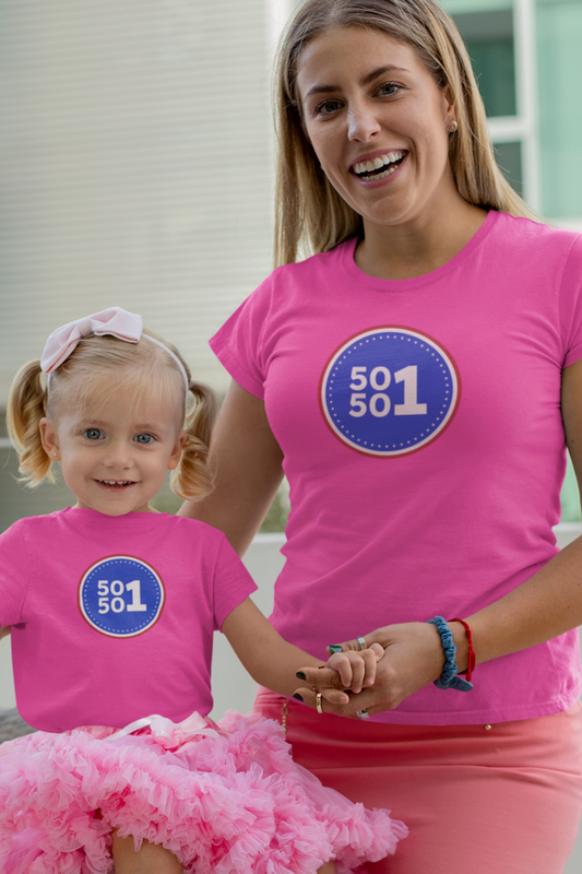 Woman and child wearing matching pink t-shirts with a blue circle design outdoors.